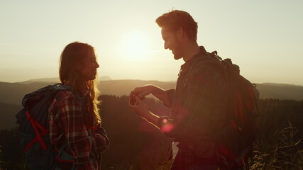 Man making woman surprise during hike. Smiling guy proposing marriage to woman 