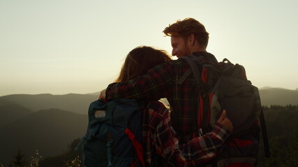 Happy woman and man hiking in mountains. Smiling guy looking at girl