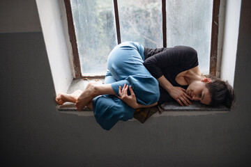 Woman lying on old and dirty window sill, solitude, mental health and depression concept.