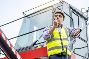 Young male engineer or manager Use of radio communication to control container load in industrial...