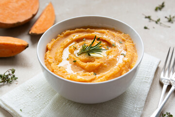 Mashed sweet potato, batata potatoes puree in bowl with butter and herbs. Thanksgiving meal.