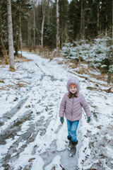 Mädchen spaziert auf winterlichem Waldweg