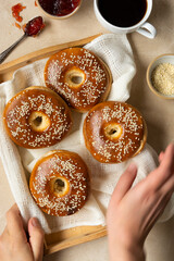 Bagels pastry buns for breakfast,with coffee cup and fruit jam. Top view, bright background, natural light.