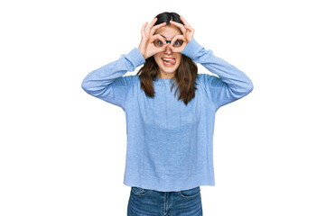 Young beautiful woman wearing casual clothes and glasses doing ok gesture like binoculars sticking tongue out, eyes looking through fingers. crazy expression.