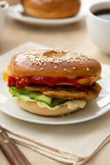 Bagel sandwich with cucumber, sauce, egg, cheese. Breakfast or lunch, closeup bagel bun served with coffee