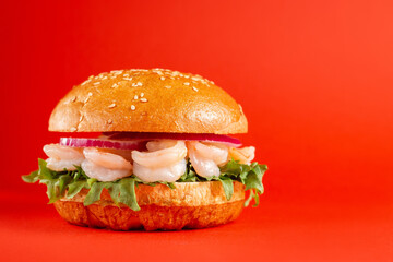 Delicious burger with shrimps on red isolated background. Tasty fresh unhealthy burgers with cheese and two patties. Fast food, unhealthy food concept.