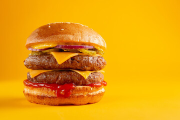Delicious burger with double beef and cheddar cheese on a yellow background. Tasty fresh unhealthy...