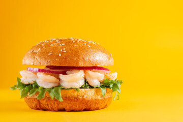 Delicious burger with shrimp, isolated on yellow background. Tasty fresh unhealthy hamburgers....