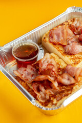 Delicious breakfast. Scrambled eggs with bacon on a yellow background