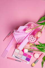 Makeup cosmetic set and hair combs on pink background