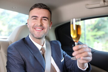 Elegant man drinking champagne in limousine  - obrazy, fototapety, plakaty