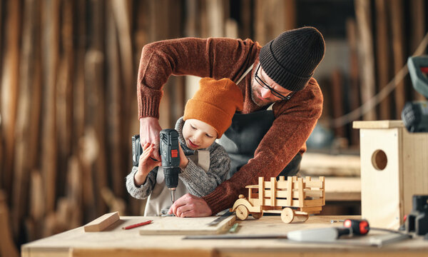 Father and son drilling wooden detail in workshop