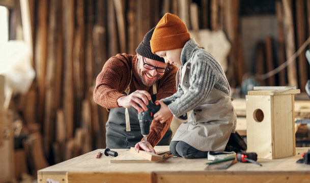 Father and son drilling wooden detail in workshop
