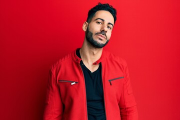 Obraz premium Young hispanic man wearing red leather jacket looking at the camera blowing a kiss on air being lovely and sexy. love expression.