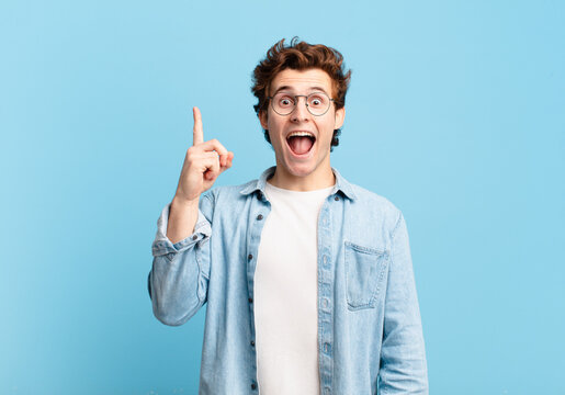 young handsome boy feeling like a happy and excited genius after realizing an idea, cheerfully raising finger, eureka!