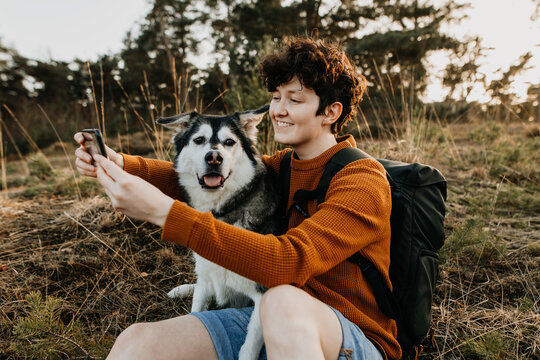 Junge Frau und Hund machen Selfie auf Reisen