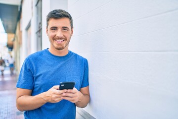 Fototapeta premium Young caucasian man smiling happy using smartphone at the city.
