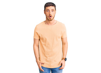 Fototapeta premium Handsome young man with bear wearing casual yellow tshirt afraid and shocked with surprise expression, fear and excited face.