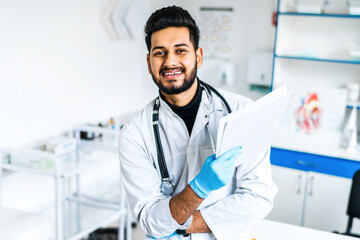 Portrait of a smiling Indian doctor at work, he looks at the camera, modern Indian medicine, health and safety
