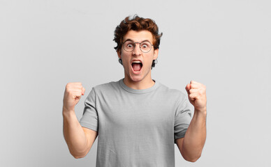 young handsome boy shouting aggressively with an angry expression or with fists clenched...