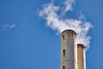 Un par de chimeneas del edificio de servicios del museo de la ciencia expulsando vapor y humo a la atmósfera
