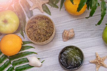 image of homemade cosmetics ingredients. aroma theme. Black mask, clay. organic cosmetics with extracts of herbs apples, lemons and oranges on white leaf green background