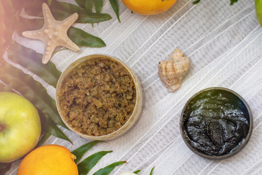 image of homemade cosmetics ingredients. aroma theme. Black mask, clay. organic cosmetics with extracts of herbs apples, lemons and oranges on white leaf green background