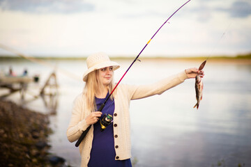 a girl fisherman in a blue dress and hat caught a perch, Selective focus