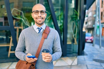 Young african american businessman using smartphone and drinking take away coffee at the city.