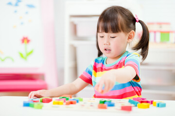 young  girl learning letter blocks for homeschooling