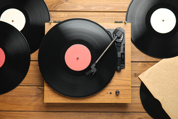 Vintage vinyl records and turntable on wooden background, flat lay