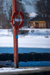 A closeup of an orange life saver ring hanging on wooden pole on the beach boulevard.