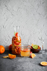 Mixed citrus lemonade in a tall glass jar. A drink made from red oranges, lemons and limes. Refreshing cold cocktails.