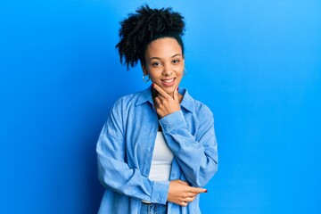 Young african american girl wearing casual clothes looking confident at the camera smiling with crossed arms and hand raised on chin. thinking positive.