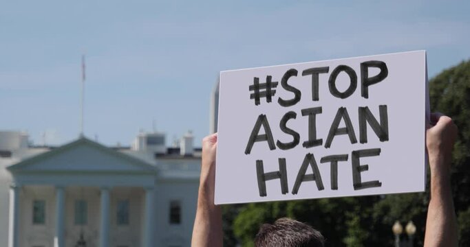 WASHINGTON, DC - Circa March, 2021 - A man waves a handmade STOP ASIAN HATE hashtag protest sign outside the White House.  	