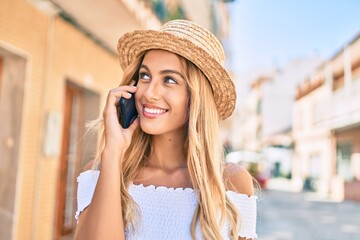 Young blonde tourist girl smiling happy talking on the smartphone at the city.