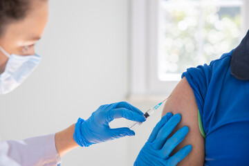 Female doctor applying a vaccine on a male patient .