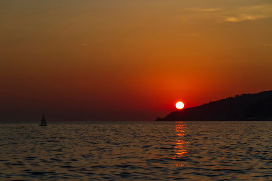 Small sailboat at sea at sunset