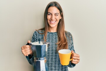 Young beautiful woman drinking italian coffee winking looking at the camera with sexy expression,...