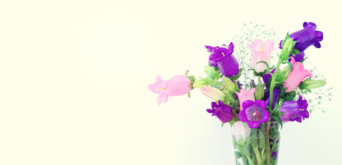 spring bouquet of purple, white and pink bell flowers over white wooden background