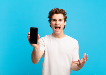 young boy looking angry, annoyed and frustrated screaming wtf or what’s wrong with you. telephone...