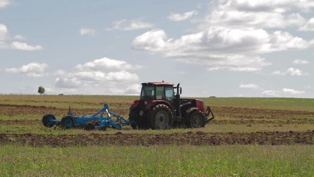 Tractor with cultivator loosens the soil and destroys weeds, preparing the field for planting.