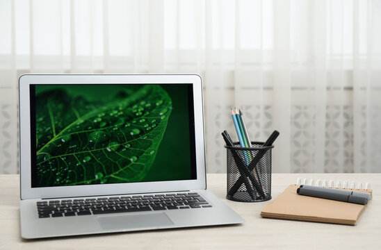 Modern laptop and supplies on wooden table indoors