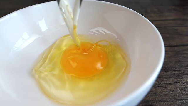 Slow motion of woman crack egg into the bowl to prepare the food