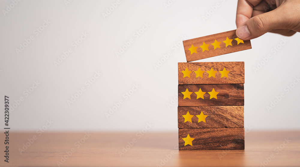 Poster hand putting five start which print screen on wooden cube block, customer satisfaction for product a