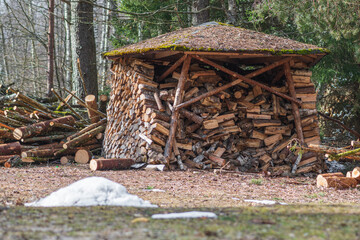 Circular or cylindrical structure, pile or stack composed of blocks, pieces or logs of wood and roof, in winter or spring with snow. The art of stacking wood for drying and storage in northern Europe