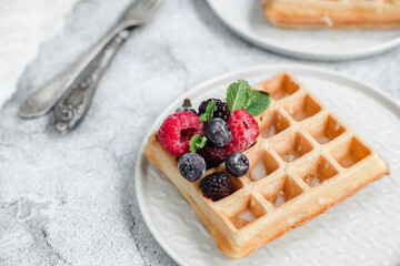 Belgian waffles with berries on a light plate.Breakfast