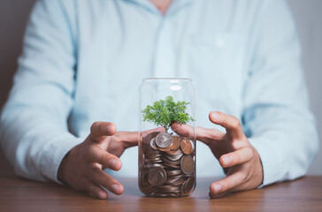 Businessman protect Tree which growth inside saving coins jar , Save money for investment and...