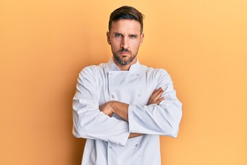 Handsome man with beard wearing professional cook uniform skeptic and nervous, disapproving...