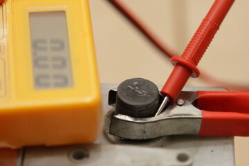 Maintenance free car battery positive pin with red terminal cleat of digital multimeter screen with zero digit, empty car battery failure